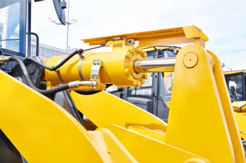 Close-up view of a front loader hydraulic cylinder and lifting arm mechanism