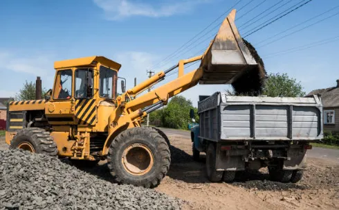 Front loader unloading gravel into a dump truck at a construction site